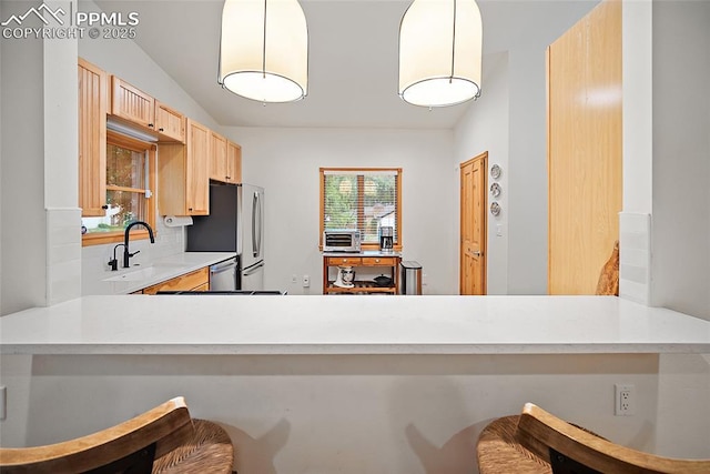 225 Laclede Ct, Colorado Springs, CO 80905 - kitchen with freestanding refrigerator, light brown cabinets, light countertops, backsplash, and a kitchen breakfast bar