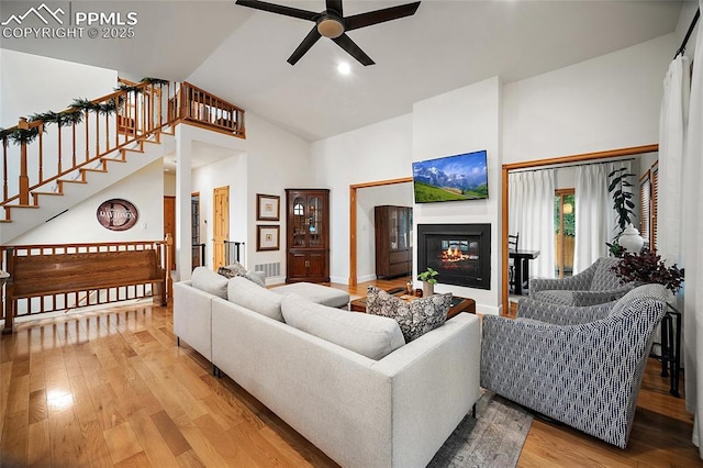 225 Laclede Ct, Colorado Springs, CO 80905 - living room with a ceiling fan, wood finished floors, high vaulted ceiling, a glass covered fireplace, and stairs