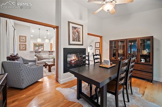 225 Laclede Ct, Colorado Springs, CO 80905 - dining room with light wood-style flooring, a multi sided fireplace, a towering ceiling, and a ceiling fan