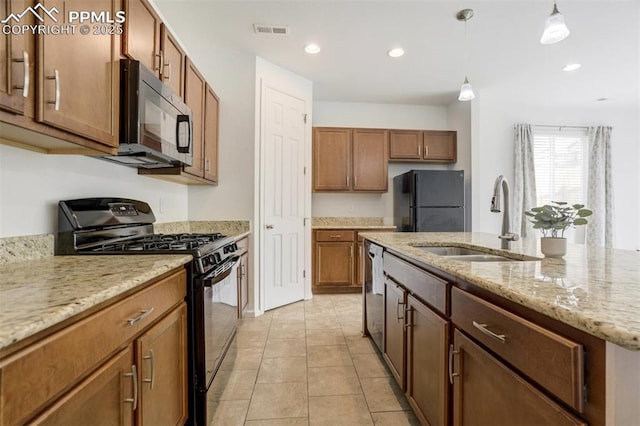 4887 Wolf Moon Dr, Colorado Springs, CO 80911 - kitchen featuring black appliances, decorative light fixtures, light stone countertops, brown cabinets, and a center island with sink
