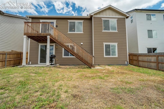 7119 Passing Sky Dr, Colorado Springs, CO 80911 - back of house with stairway, a fenced backyard, a wooden deck, and board and batten siding