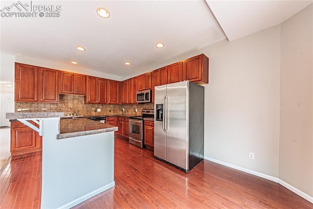 2513 Gilpin Ave, Colorado Springs, CO 80910 - kitchen featuring appliances with stainless steel finishes, decorative backsplash, dark wood-type flooring, recessed lighting, and a kitchen breakfast bar