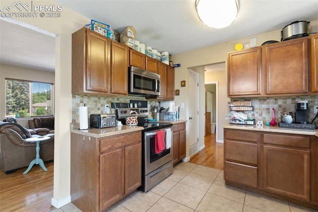 614 Bickley St, Colorado Springs, CO 80911 - kitchen featuring appliances with stainless steel finishes, light countertops, backsplash, and brown cabinetry