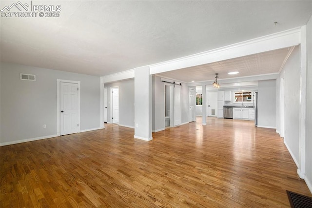 1406 N Foote Ave, Colorado Springs, CO 80909 - unfurnished living room featuring a barn door and light wood-type flooring
