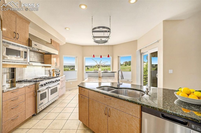 19170 Lochmere Ct, Monument, CO 80132 - kitchen featuring appliances with stainless steel finishes, dark stone counters, wall chimney exhaust hood, recessed lighting, and light tile patterned floors