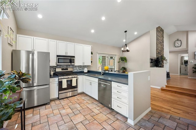 3470 Whimbrel Ln, Colorado Springs, CO 80906 - kitchen featuring appliances with stainless steel finishes, vaulted ceiling, dark countertops, light stone finish flooring, and open shelves