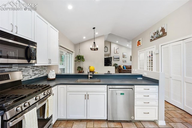 3470 Whimbrel Ln, Colorado Springs, CO 80906 - kitchen with stainless steel appliances, dark countertops, lofted ceiling, white cabinets, and hanging light fixtures