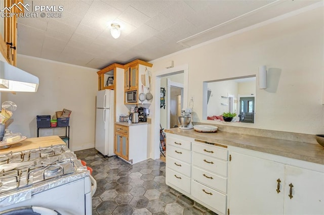 414 Griffin Ave, Canon City, CO 81212 - kitchen with freestanding refrigerator, built in microwave, glass insert cabinets, light countertops, and crown molding