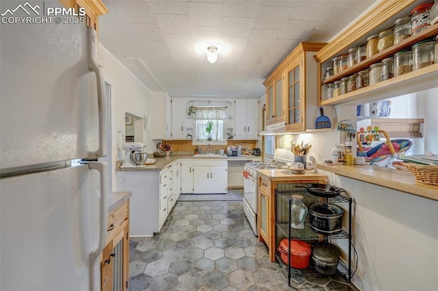 414 Griffin Ave, Canon City, CO 81212 - kitchen with white appliances, under cabinet range hood, light countertops, glass insert cabinets, and tile patterned floors