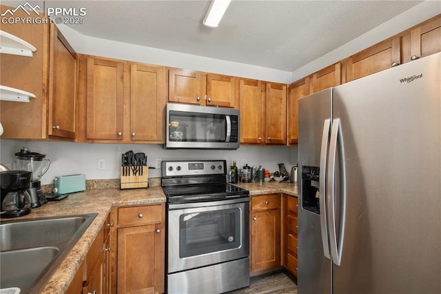 7104 Ash Creek Hts Unit 203, Colorado Springs, CO 80922 - kitchen featuring appliances with stainless steel finishes, brown cabinetry, and wood finished floors