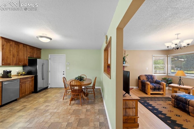 811 N Baldwin St, Woodland Park, CO 80863 - kitchen featuring stainless steel appliances, a textured ceiling, open floor plan, brown cabinets, and a chandelier