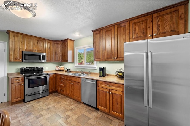 811 N Baldwin St, Woodland Park, CO 80863 - kitchen featuring stainless steel appliances, brown cabinets, light stone finish flooring, light countertops, and a textured ceiling