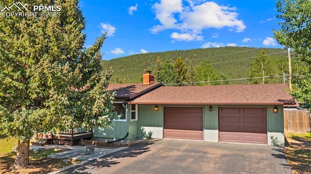 811 N Baldwin St, Woodland Park, CO 80863 - ranch-style home with asphalt driveway, a wooded view, a chimney, and a deck with mountain view
