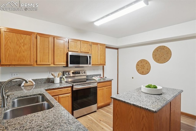4903 Wainwright Dr, Colorado Springs, CO 80911 - kitchen with appliances with stainless steel finishes, light wood-type flooring, a center island, and light stone counters
