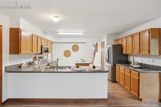 4903 Wainwright Dr, Colorado Springs, CO 80911 - kitchen featuring appliances with stainless steel finishes, light wood-style floors, a peninsula, and dark stone countertops