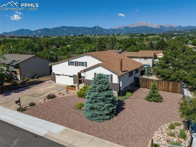 4032 E Darby Cir, Colorado Springs, CO 80907 - view of front of house with a mountain view, driveway, an attached garage, and roof with shingles