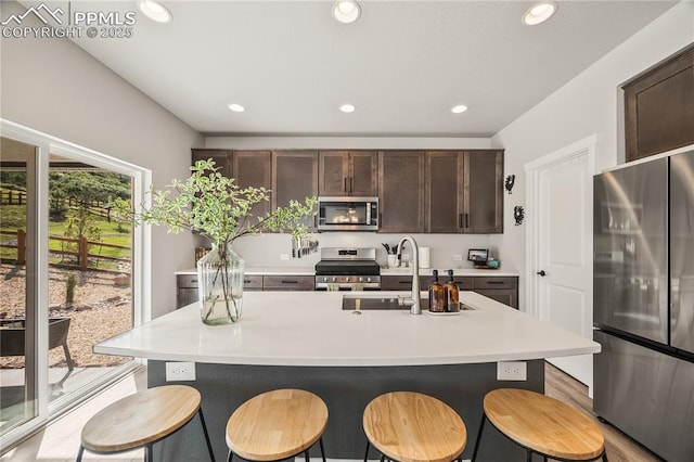 5446 Mesa Top Dr, Monument, CO 80132 - kitchen featuring stainless steel appliances, a breakfast bar, dark brown cabinets, light countertops, and recessed lighting