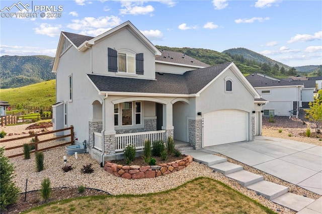 5446 Mesa Top Dr, Monument, CO 80132 - view of front facade featuring a porch, a mountain view, stucco siding, concrete driveway, and a shingled roof