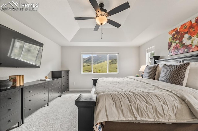 5446 Mesa Top Dr, Monument, CO 80132 - bedroom featuring a raised ceiling, light colored carpet, multiple windows, and a ceiling fan