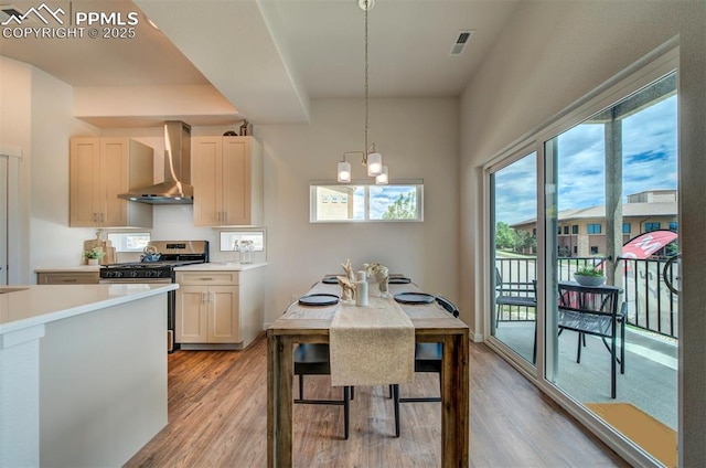 2186 Keara Hts, Colorado Springs, CO 80919 - kitchen with wall chimney exhaust hood, gas range, light wood-type flooring, and a chandelier