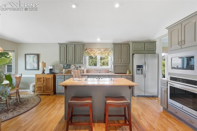 1690 Doe Run Pt, Colorado Springs, CO 80919 - kitchen featuring stainless steel appliances, light countertops, plenty of natural light, a breakfast bar area, and recessed lighting