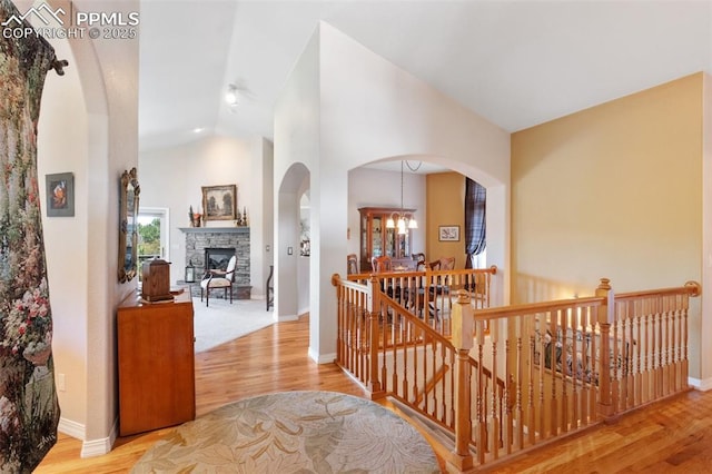 1690 Doe Run Pt, Colorado Springs, CO 80919 - hallway with an upstairs landing, vaulted ceiling, wood finished floors, arched walkways, and a chandelier