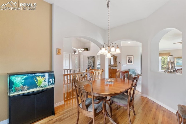 1690 Doe Run Pt, Colorado Springs, CO 80919 - dining room featuring light wood-style flooring, arched walkways, high vaulted ceiling, and a chandelier