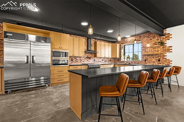 11910 Green Acres Ln, Colorado Springs, CO 80908 - kitchen featuring built in appliances, wall chimney exhaust hood, brick wall, dark countertops, and finished concrete flooring