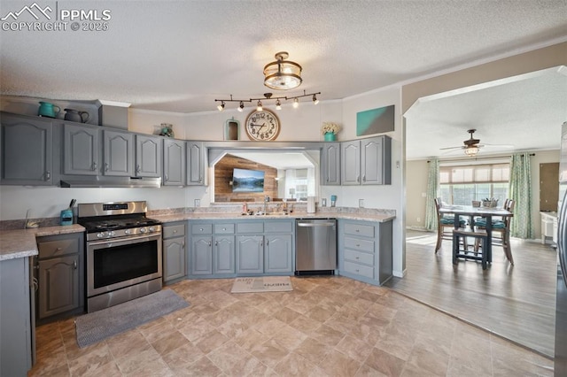 5664 Southfork Dr, Peyton, CO 80831 - kitchen with stainless steel appliances, under cabinet range hood, gray cabinets, ornamental molding, and a textured ceiling