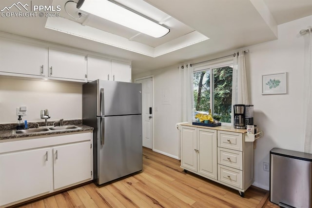 906 Bowser Dr, Colorado Springs, CO 80909 - kitchen with freestanding refrigerator, light wood-style flooring, white cabinetry, a raised ceiling, and refrigerator