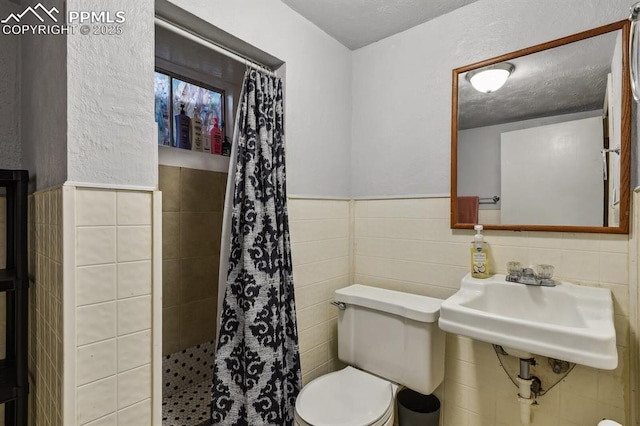 906 Bowser Dr, Colorado Springs, CO 80909 - full bath with tile walls, a tile shower, wainscoting, and a textured ceiling