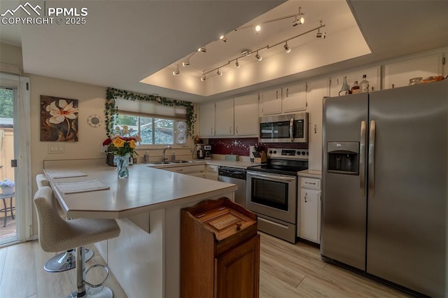 2021 N Academy Blvd, Colorado Springs, CO 80909 - kitchen with stainless steel appliances, a peninsula, light countertops, light wood-style flooring, and white cabinetry