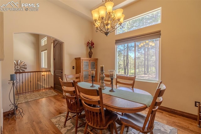 15324 Pole Pine Pt, Colorado Springs, CO 80908 - dining area with arched walkways, wood finished floors, a chandelier, and a high ceiling