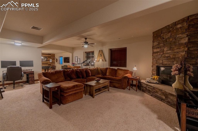 15324 Pole Pine Pt, Colorado Springs, CO 80908 - living room featuring light colored carpet, a stone fireplace, a desk, ceiling fan, and arched walkways