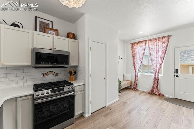 1773 Herd St, Colorado Springs, CO 80910 - kitchen with appliances with stainless steel finishes, light wood-type flooring, light countertops, and decorative backsplash