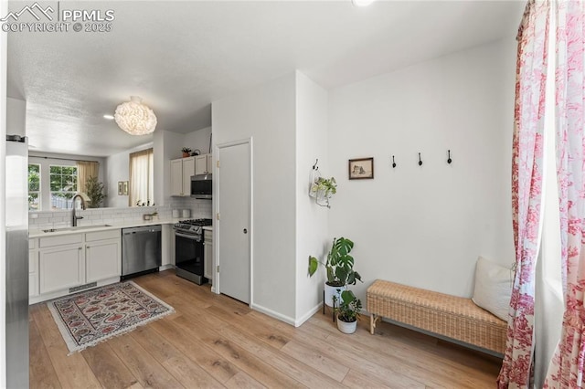 1773 Herd St, Colorado Springs, CO 80910 - kitchen with appliances with stainless steel finishes, decorative backsplash, light wood-type flooring, and light countertops