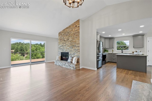 110 Fox Hill Ln, Colorado Springs, CO 80919 - unfurnished living room featuring high vaulted ceiling, a chandelier, wood finished floors, and a stone fireplace