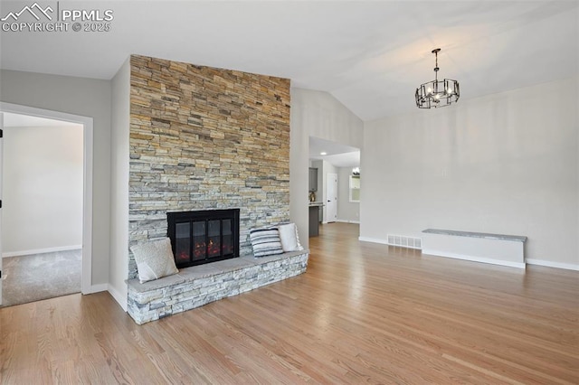 110 Fox Hill Ln, Colorado Springs, CO 80919 - unfurnished living room featuring a chandelier, wood finished floors, lofted ceiling, and a stone fireplace
