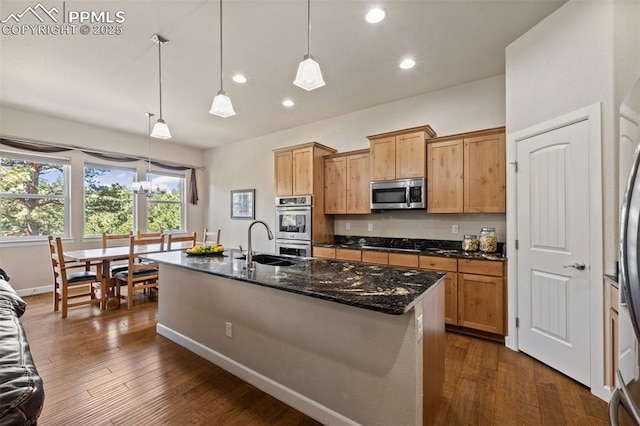 15704 Pole Pine Pt, Colorado Springs, CO 80908 - kitchen with appliances with stainless steel finishes, recessed lighting, dark wood finished floors, an island with sink, and dark stone counters