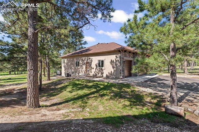 15704 Pole Pine Pt, Colorado Springs, CO 80908 - view of home's exterior featuring a garage, driveway, a yard, and stucco siding