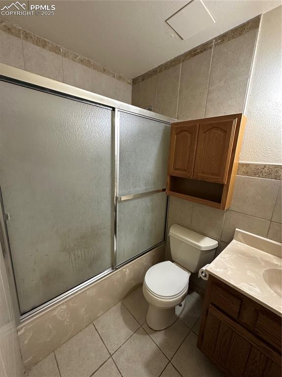 131 Cornell St, Colorado Springs, CO 80911 - bathroom featuring tile walls, combined bath / shower with glass door, vanity, and tile patterned flooring
