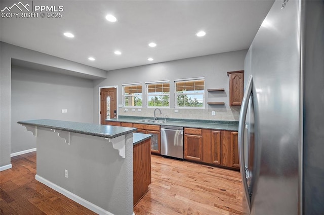354 Corona Ave, Palmer Lake, CO 80133 - kitchen with appliances with stainless steel finishes, a breakfast bar area, brown cabinets, light wood-style flooring, and recessed lighting