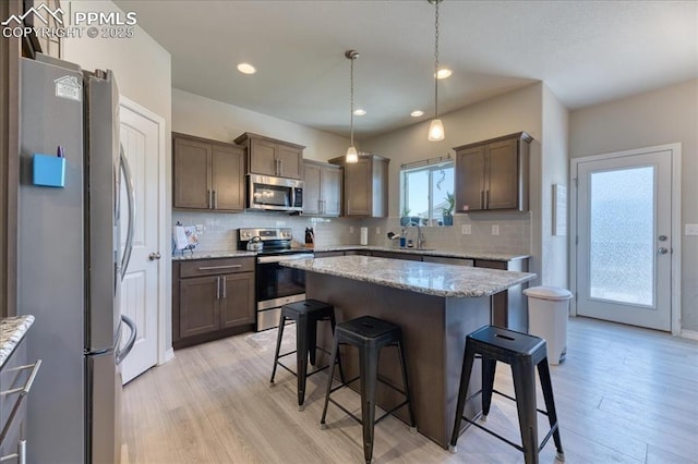 8285 Lodge Grass Way, Colorado Springs, CO 80908 - kitchen with stainless steel appliances, a kitchen breakfast bar, light wood-type flooring, backsplash, and dark brown cabinetry