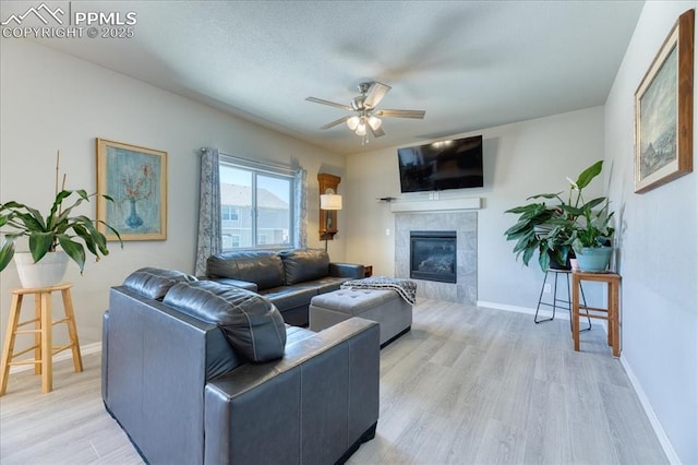 8285 Lodge Grass Way, Colorado Springs, CO 80908 - living room with a ceiling fan, light wood-style floors, and a tiled fireplace