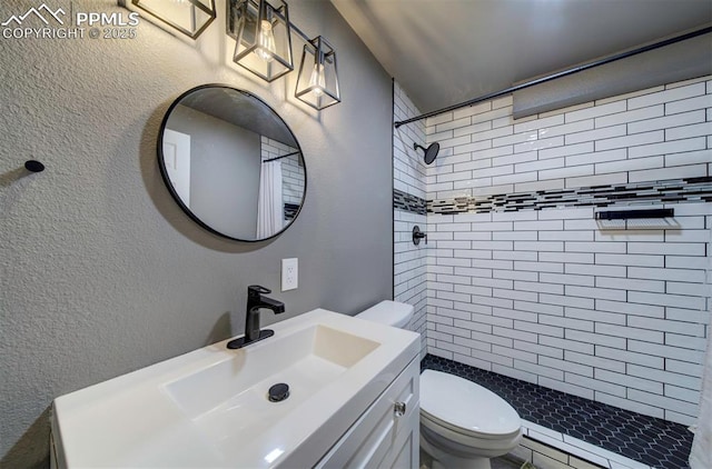 4530 W Jet Wing Cir, Colorado Springs, CO 80916 - bathroom featuring tiled shower, a textured wall, and vanity