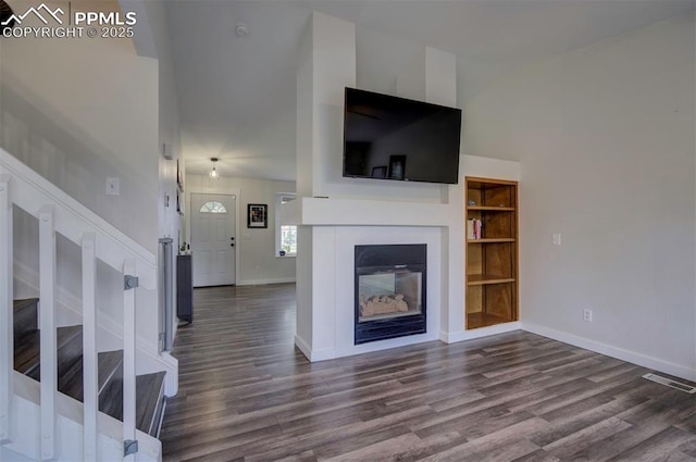 4530 W Jet Wing Cir, Colorado Springs, CO 80916 - unfurnished living room with high vaulted ceiling, dark wood-type flooring, stairway, and built in features