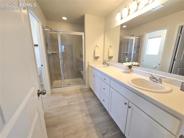 8136 Kittrick Pl, Peyton, CO 80831 - full bathroom featuring double vanity, a shower stall, wood finished floors, and recessed lighting