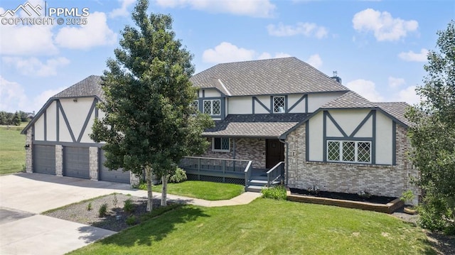 780 Mission Hill Way, Colorado Springs, CO 80921 - tudor home featuring a front lawn, concrete driveway, stucco siding, covered porch, and brick siding