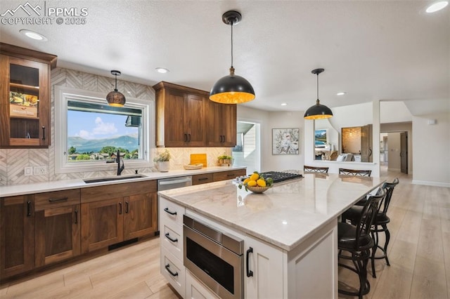 780 Mission Hill Way, Colorado Springs, CO 80921 - kitchen featuring stainless steel appliances, a kitchen bar, tasteful backsplash, glass insert cabinets, and decorative light fixtures