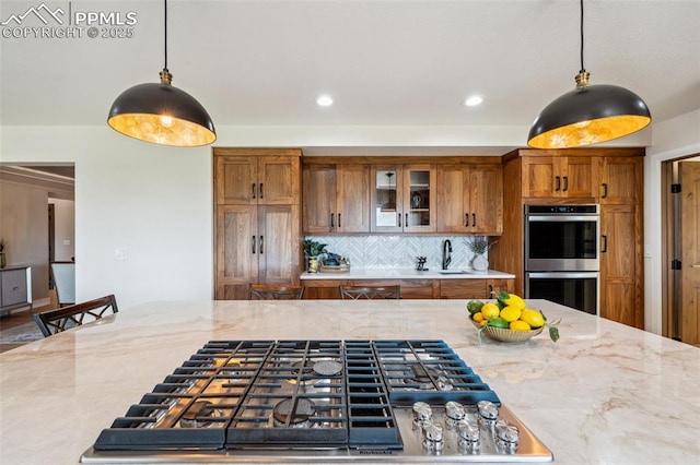 780 Mission Hill Way, Colorado Springs, CO 80921 - kitchen with appliances with stainless steel finishes, brown cabinetry, decorative light fixtures, light stone counters, and recessed lighting